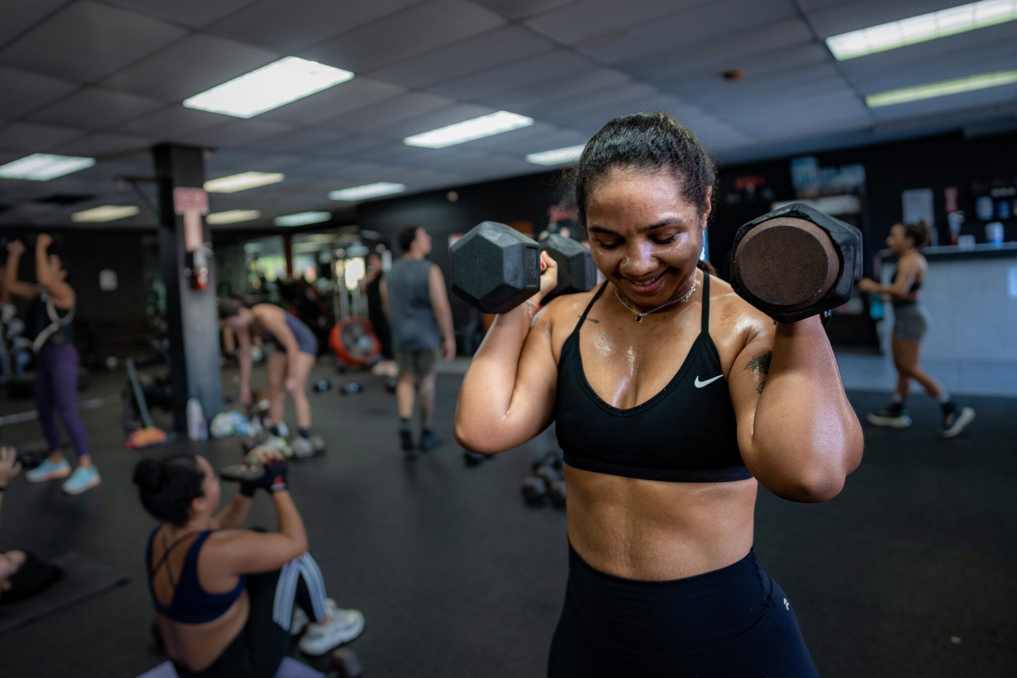 Clienta del gym Guasábara Fitness levantando pesas durante un entrenamiento grupal en Trujillo Alto, Puerto Rico.