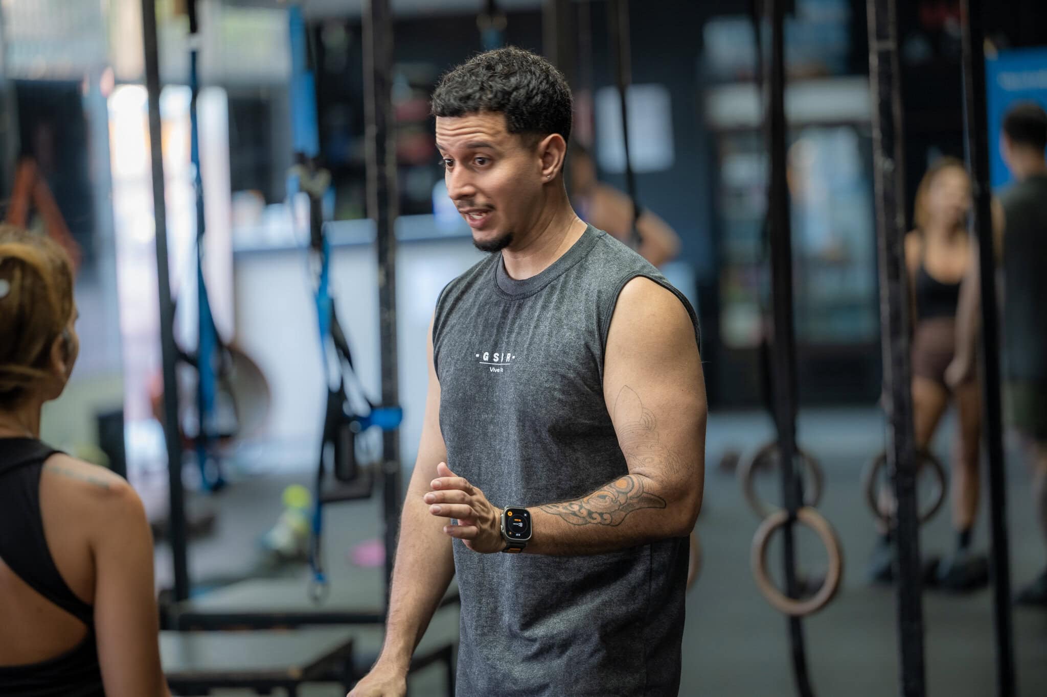 Jorge “Pototo” Ojeda, entrenador personal de Guasábara Fitness, explicando una rutina de ejercicios a una clienta en Trujillo Alto, Puerto Rico.